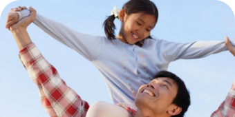 Man holding a girl over his shoulders, both are smiling.