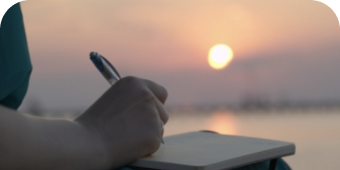 Person holding a pen and writing on a notebook.